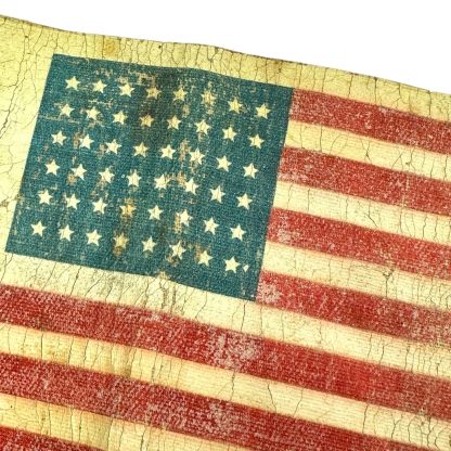 A worn and aged WWII US Airborne invasion armband featuring a faded American flag design with 48 stars, printed on a yellowed fabric background with visible cracks and creases.