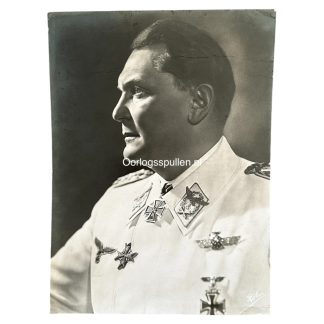 Black and white portrait photograph of Hermann Göring, a high-ranking Nazi official, wearing a white military uniform adorned with various medals and insignia. The photograph is taken from a side profile, showing his facial features in strong lighting. The watermark 'Oorlogsspullen.nl' is visible in the center of the image.