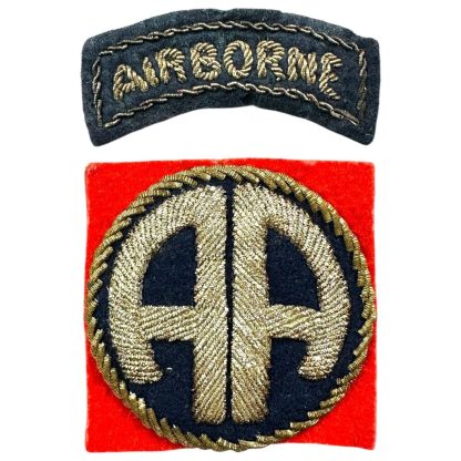 A World War II-era U.S. 82nd Airborne Division bullion patch, British-made. The patch consists of a curved black tab with 'AIRBORNE' embroidered in gold bullion thread and a square red patch featuring a gold bullion 'AA' insignia on a dark blue background, surrounded by gold braiding.