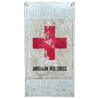 A vintage American Red Cross wooden sign from World War Two, featuring a red cross symbol on a weathered white background with the words 'AMERICAN RED CROSS' printed below. The sign shows significant aging, with chipped paint and worn edges, mounted on a wooden board.