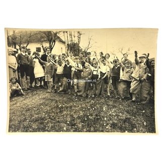 Original World War II-era photograph showing a group of German children and youth giving the Hitler salute, some dressed in casual clothing and others in early Hitler Youth-style attire. Likely taken during a local Nazi-organized event or youth activity, this rare image captures the widespread ideological influence on civilians during the Third Reich. A historically significant and collectible photo reflecting Nazi propaganda’s reach into everyday life and the indoctrination of children under the National Socialist regime.