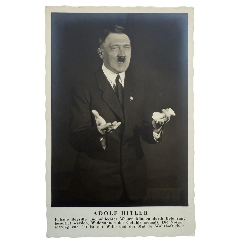 Cartolina storica in bianco e nero di propaganda che ritrae Adolf Hitler mentre gesticola con entrambe le mani durante un discorso. Indossa un abito scuro con cravatta. Didascalia in tedesco sotto l’immagine con una citazione attribuita a Hitler. Fotografia d’epoca dell’era nazista.