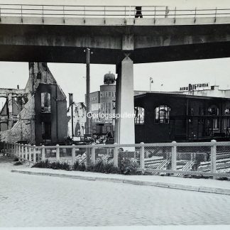 Historische foto van Dordrecht in mei 1940 na het Duitse bombardement tijdens de Tweede Wereldoorlog. Te zien zijn verwoeste gebouwen, ruïnes en beschadigde spoorinfrastructuur bij station Dordrecht, met een brugconstructie op de voorgrond.