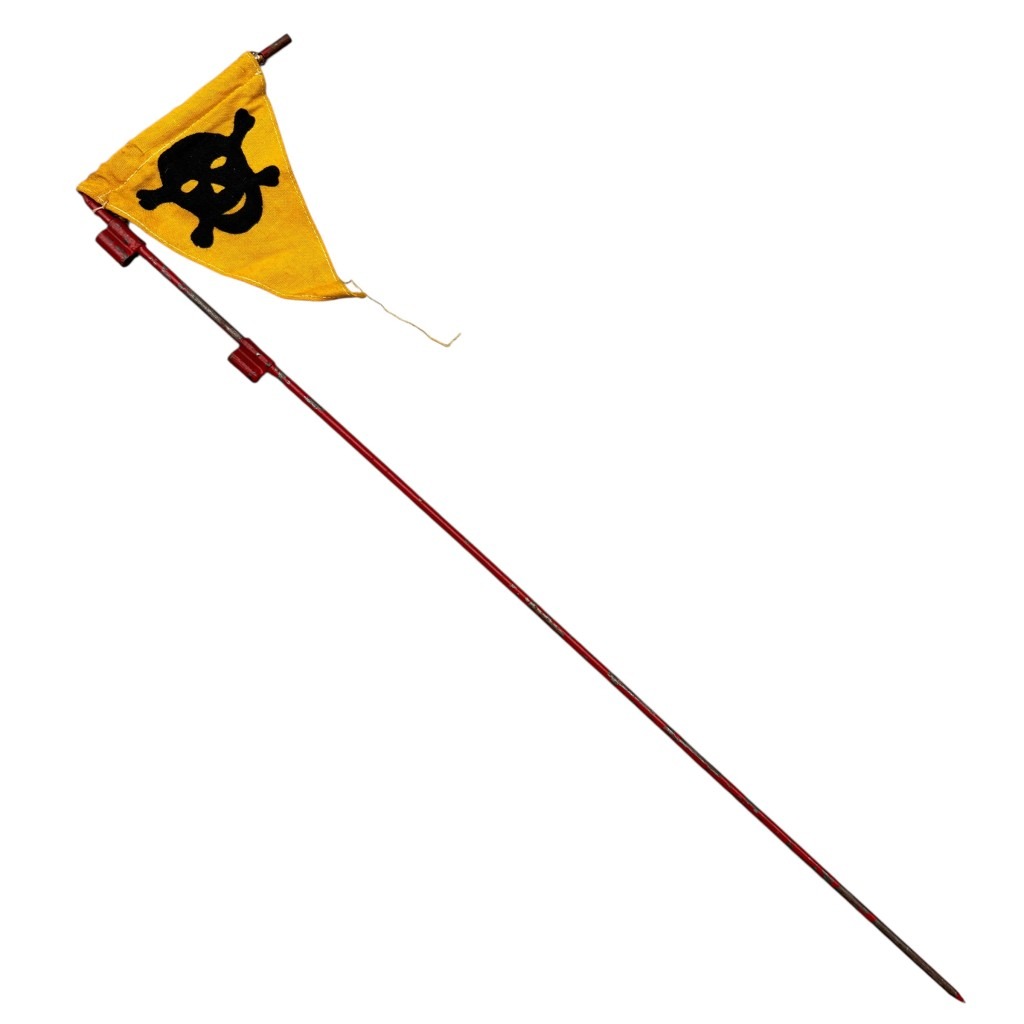 Original WWII German gas warning flag on pole, featuring a triangular yellow cloth with a black skull and crossbones symbol, mounted on a long red-painted metal shaft with a pointed tip for ground placement, used by German forces to signal chemical contamination zones.