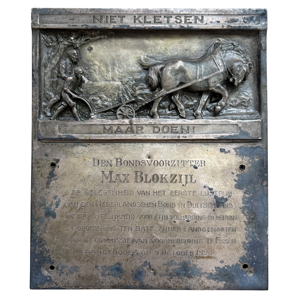 Originele metalen plaquette uit 1926, gewijd aan Max Blokzijl, voorzitter van de Nederlandschen Bond in Duitschland, met reliëfafbeelding van boer met paard en ploeg, inscriptie “Niet kletsen maar doen”, historisch NSB-verzamelobject.