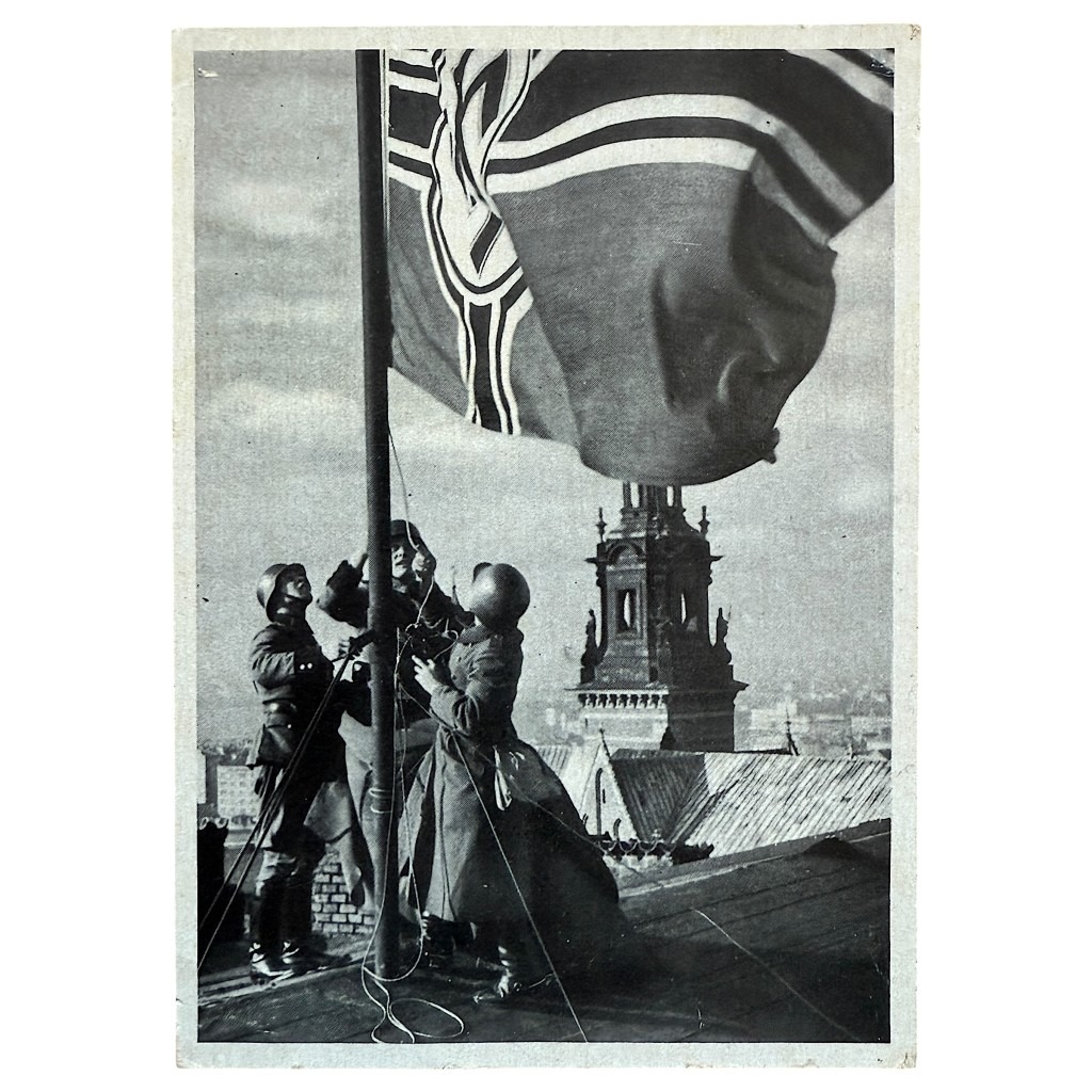 Oryginalna pocztówka z II wojny światowej – niemiecka SS-Polizei w Krakowie, Polska. Rzadkie historyczne zdjęcie żołnierzy wznoszących flagę, autentyczny kolekcjonerski przedmiot militaria z okresu Trzeciej Rzeszy, unikalna pamiątka dla pasjonatów historii wojskowej.
