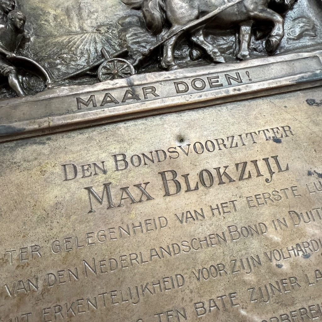 Originele metalen plaquette uit 1926, gewijd aan Max Blokzijl, voorzitter van de Nederlandschen Bond in Duitschland, met reliëfafbeelding van boer met paard en ploeg, inscriptie “Niet kletsen maar doen”, historisch NSB-verzamelobject.