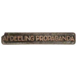 Oud metalen bord met de tekst "Afdeeling Propaganda", afkomstig uit de periode van de NSB (Nationaal-Socialistische Beweging), gebruikt als historisch propagandabord in Nederland tijdens de Tweede Wereldoorlog.