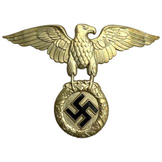 Original WWII German NSKK helmet eagle insignia by Ferdinand Wagner (RZM M1/8), authentic metal National Socialist Motor Corps eagle badge with outstretched wings, oak leaf wreath and swastika design, two original mounting pins intact — rare NSKK militaria collectible for World War II collectors.