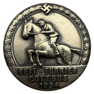 1934 Reit-Turnier Cottbus German equestrian badge with rider relief, leaf border, and historical swastika emblem; original pinback—WWII-era German militaria collectors item.