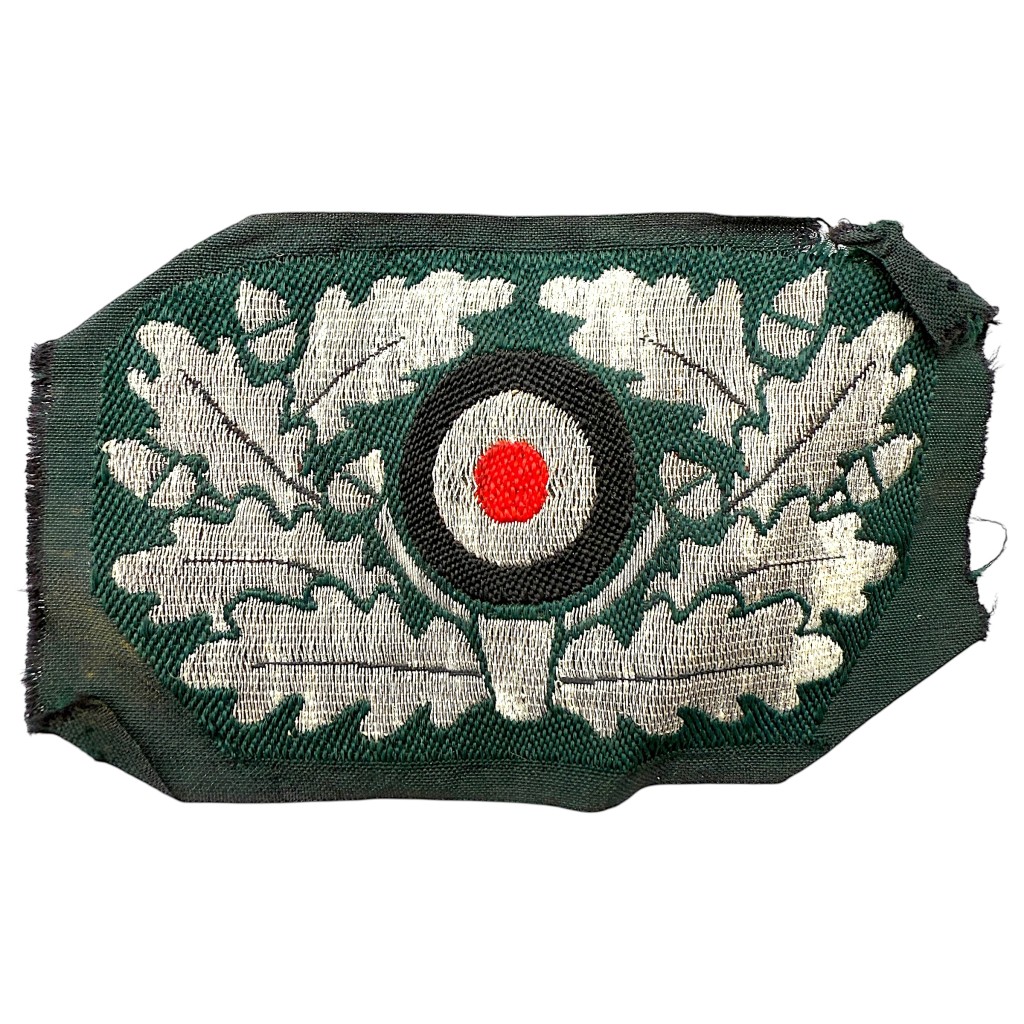 Original WWII German Wehrmacht (WH) flatwire officer’s visor cap cockade in mint condition, featuring silver oak leaf embroidery with red, white, and black roundel — authentic World War Two German insignia for militaria and WWII collectors.