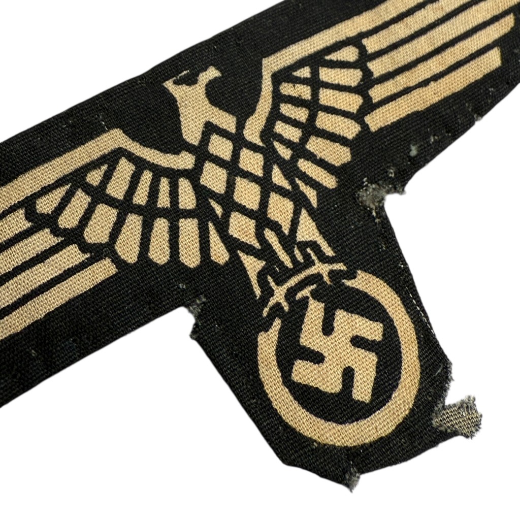 Original late-war Waffen-SS sleeve eagle, printed on black cotton fabric with eagle and swastika design. Authentic WWII German cloth insignia in worn, field-used condition — rare late-war variant sought after by Waffen-SS and military uniform collectors.