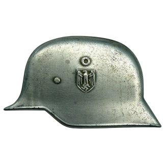 German WWII metal helmet emblem with stylized steel helmet and original fastening tabs for use on photo albums.