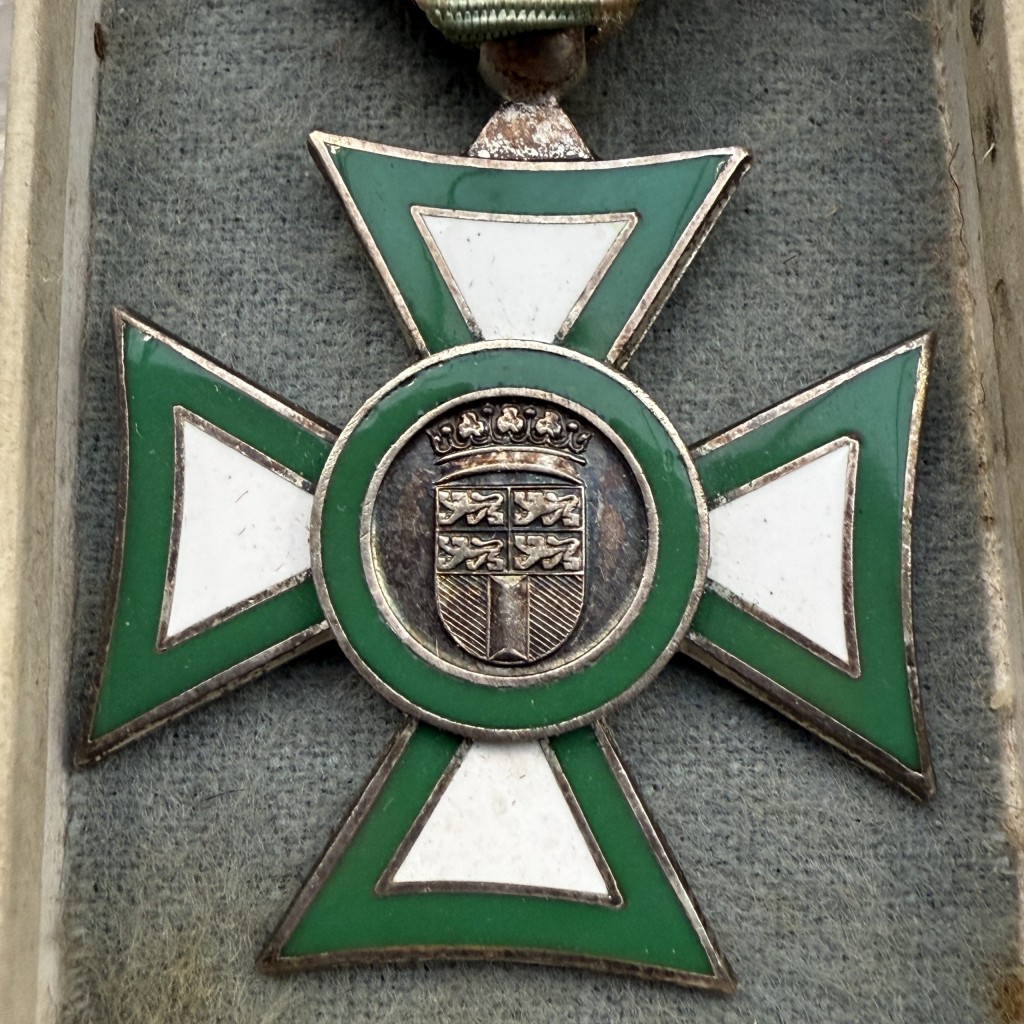 Close up van zeldzame originele herdenkingsmedaille Burgerwacht Rotterdam 1940 in groen geëmailleerd kruis met wit emaille, zilverkleurige rand, origineel lint en bewaardoos van Koninklijke Begeer Voorschoten, Nederlandse oorlogsgeschiedenis militaria.