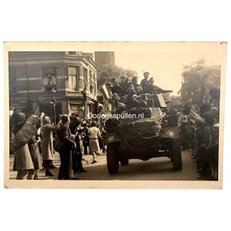 Originele bevrijdingsfoto uit Bussum in postkaartformaat, Tweede Wereldoorlog 1945, geallieerde militairen rijden door Bussum en worden begroet door juichende Nederlandse burgers, historisch WOII bevrijdingsmoment Nederland.