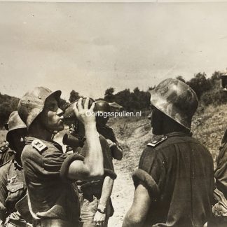 Original WWII German photograph of soldiers from the Panzergrenadier Division Großdeutschland taking a rest in the field, one soldier drinking from a canteen, wearing rare camouflage-painted M42 steel helmets, official German press photo by Kriegsberichter Peiffer dated 14 August 1944, collectible Wehrmacht militaria photo, size 18 x 13 cm.