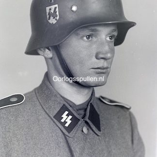 Unpublished World War II glass negative featuring a studio portrait of a young Waffen-SS soldier in full uniform with helmet and SS collar tabs, highly detailed original wartime military photograph on glass, rare WWII German military photography collectible for historians and collectors.