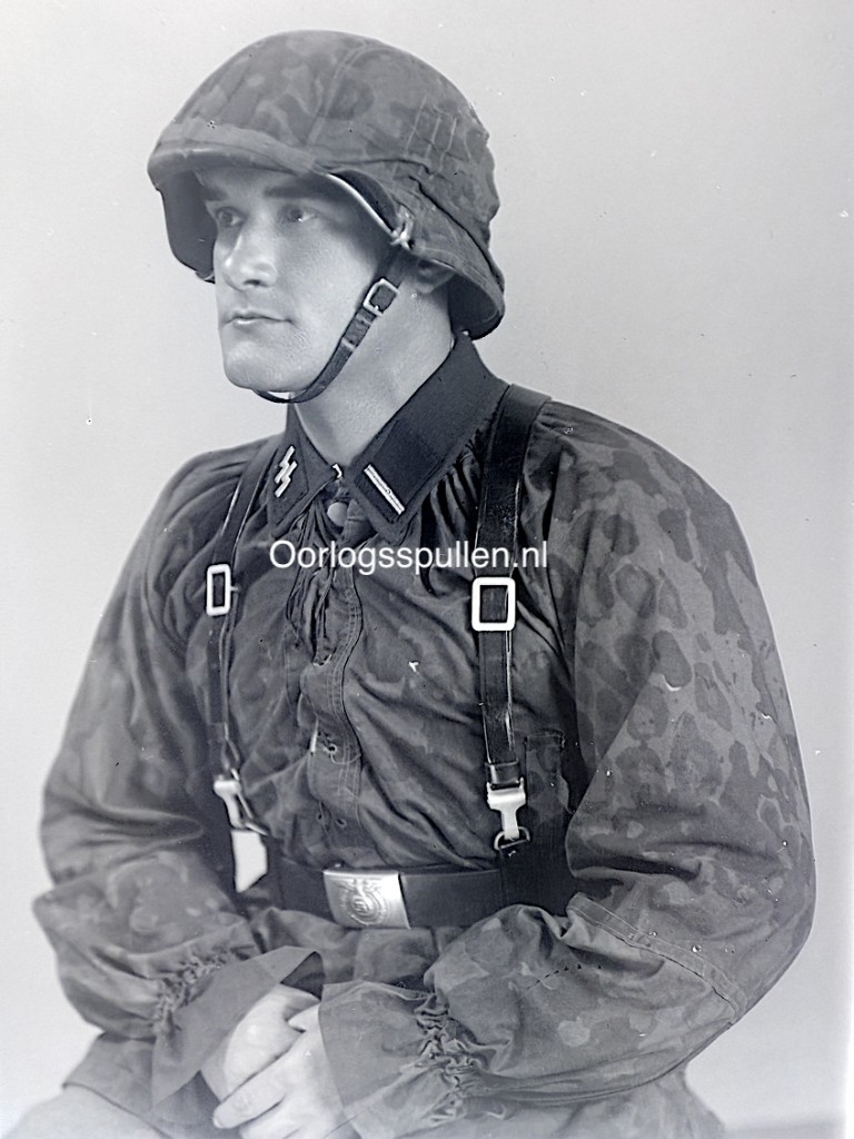 Unpublished World War II glass negative showing a Waffen-SS soldier in camouflage uniform with camouflage helmet cover, detailed studio portrait with SS collar tabs, combat gear and straps visible, rare original WWII German Waffen-SS military photography collectible for advanced collectors and historians.