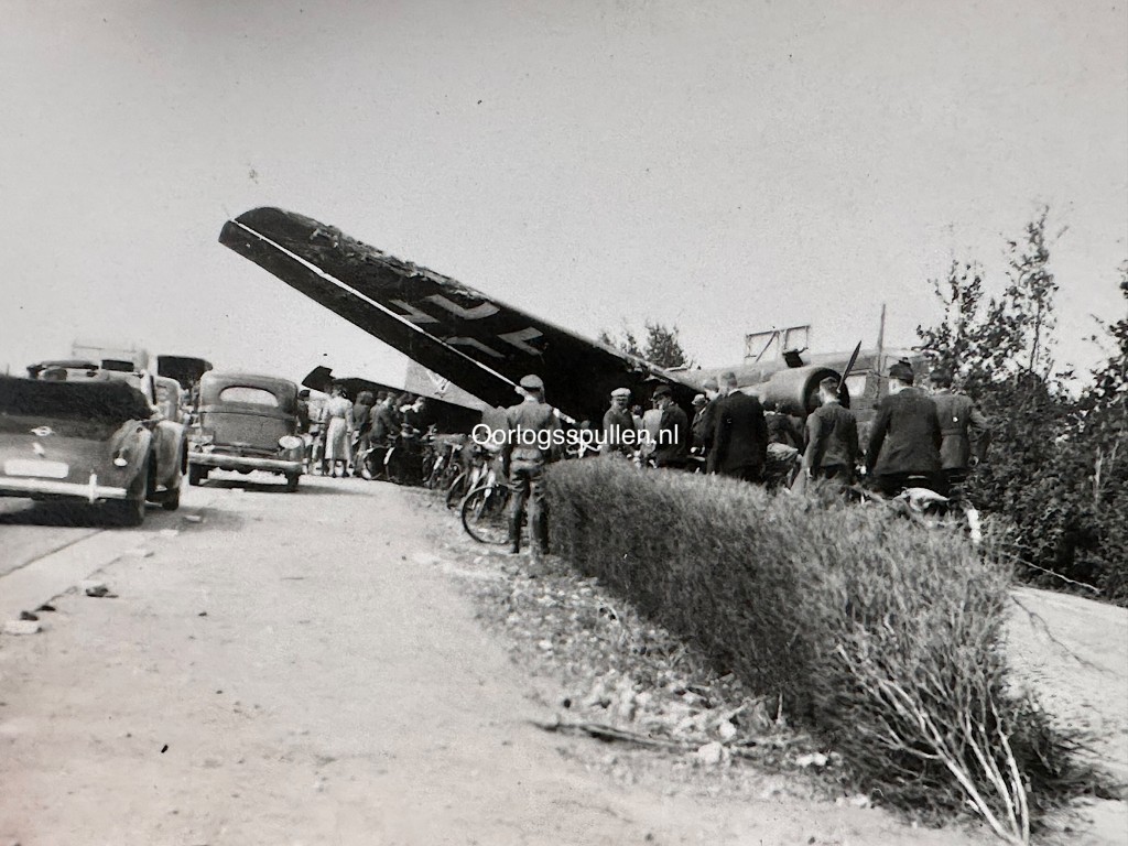 Meidagen 1940 foto van neergestort Duits vliegtuig in de omgeving van Rotterdam/Delft, met Nederlandse militairen en burgers bij het wrak tijdens de Duitse inval in Nederland – originele 9 x 6 cm Tweede Wereldoorlog foto, verzamelobject voor liefhebbers van mei 1940 fotografie.